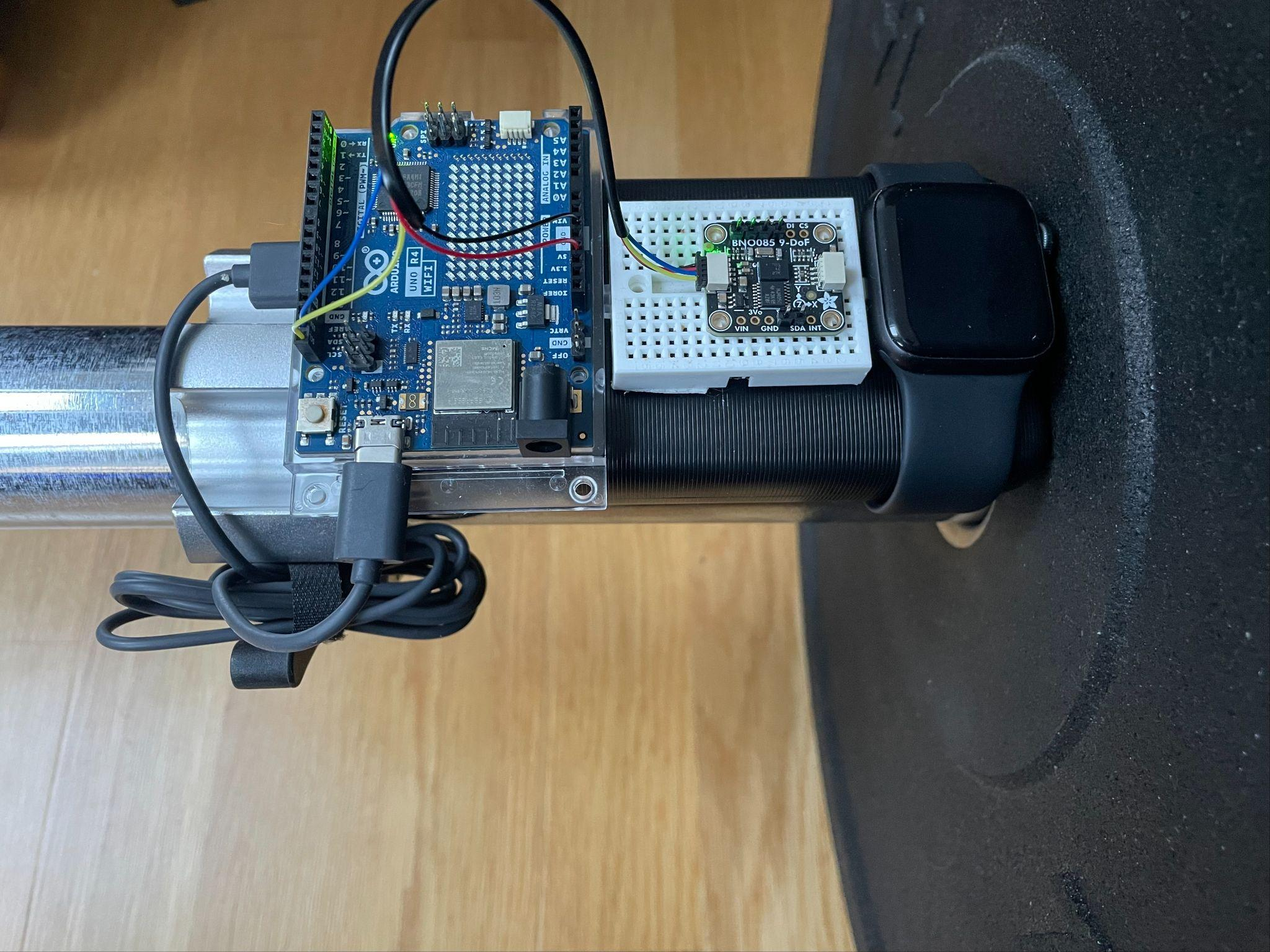 The BarSpeed prototype mounted on a barbell beside an Apple Watch.